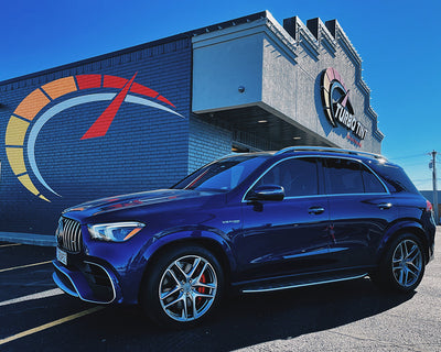 Blue SUV windshield and front and back automotive window tint sunny outside in front of building 